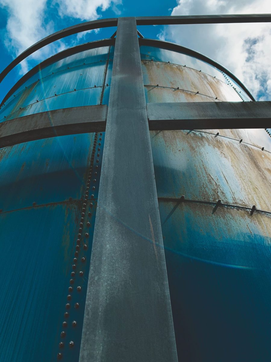 A close-up low angle shot of a rusty steel water tank against a bright blue sky in Alkmaar, Netherlands.